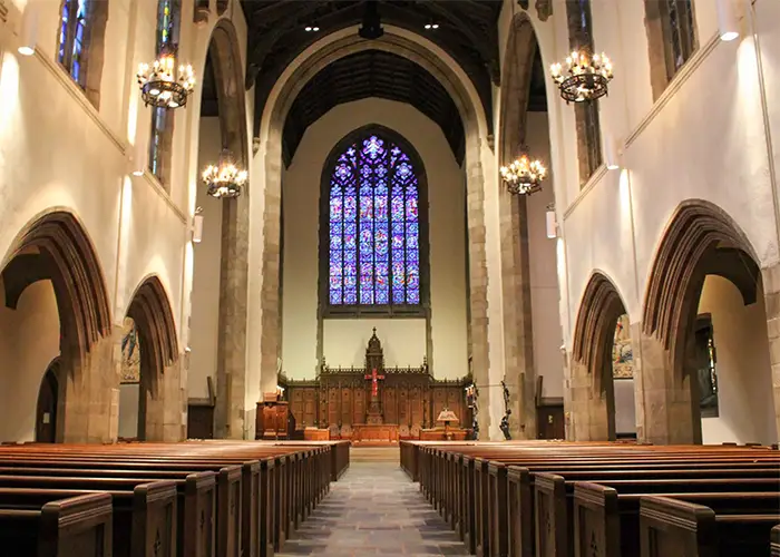 Church sanctuary with pews, chandeliers, and stained glass